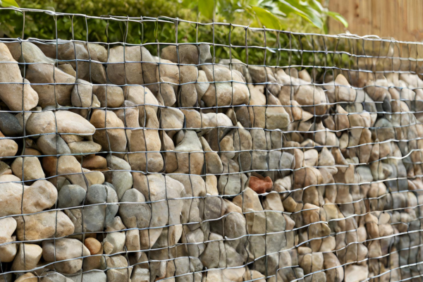 A close up of a gabion wall. It shows rocks contained in a metal container.