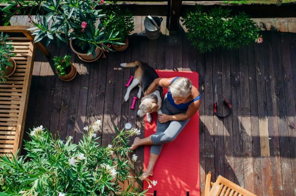 A woman and her dog sitting in the shade on a garden deck