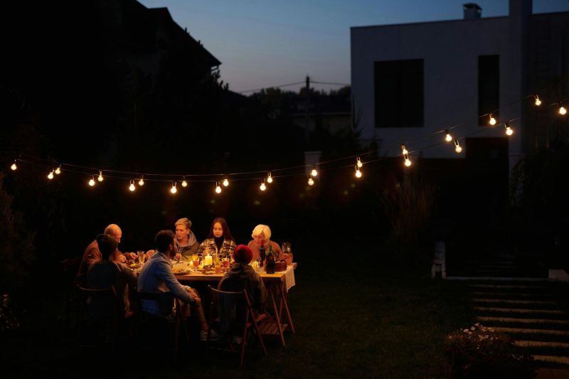 lighting-in-courtyard-garden lights hanging over a table people are sitting at in a garden